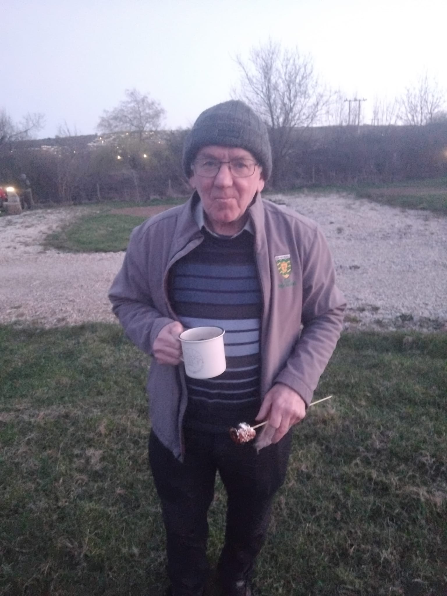 Dad by the bonfire at dusk, mug in hand and a marshmallow toasting